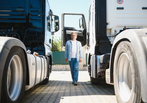 Happy confident male driver standing in front on his truck.